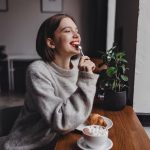 dama pelo corto sueter gris muerde cucharadita retrato nina labios rojos sentada cafeteria disfrutan