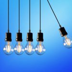 Bombilla encendida sobre fondo de facturas de electricidad representando el ahorro energético