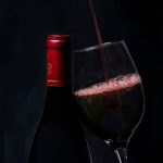 Copas de vino tinto con viñedos al fondo