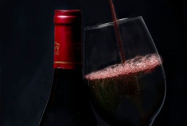 Copas de vino tinto con viñedos al fondo